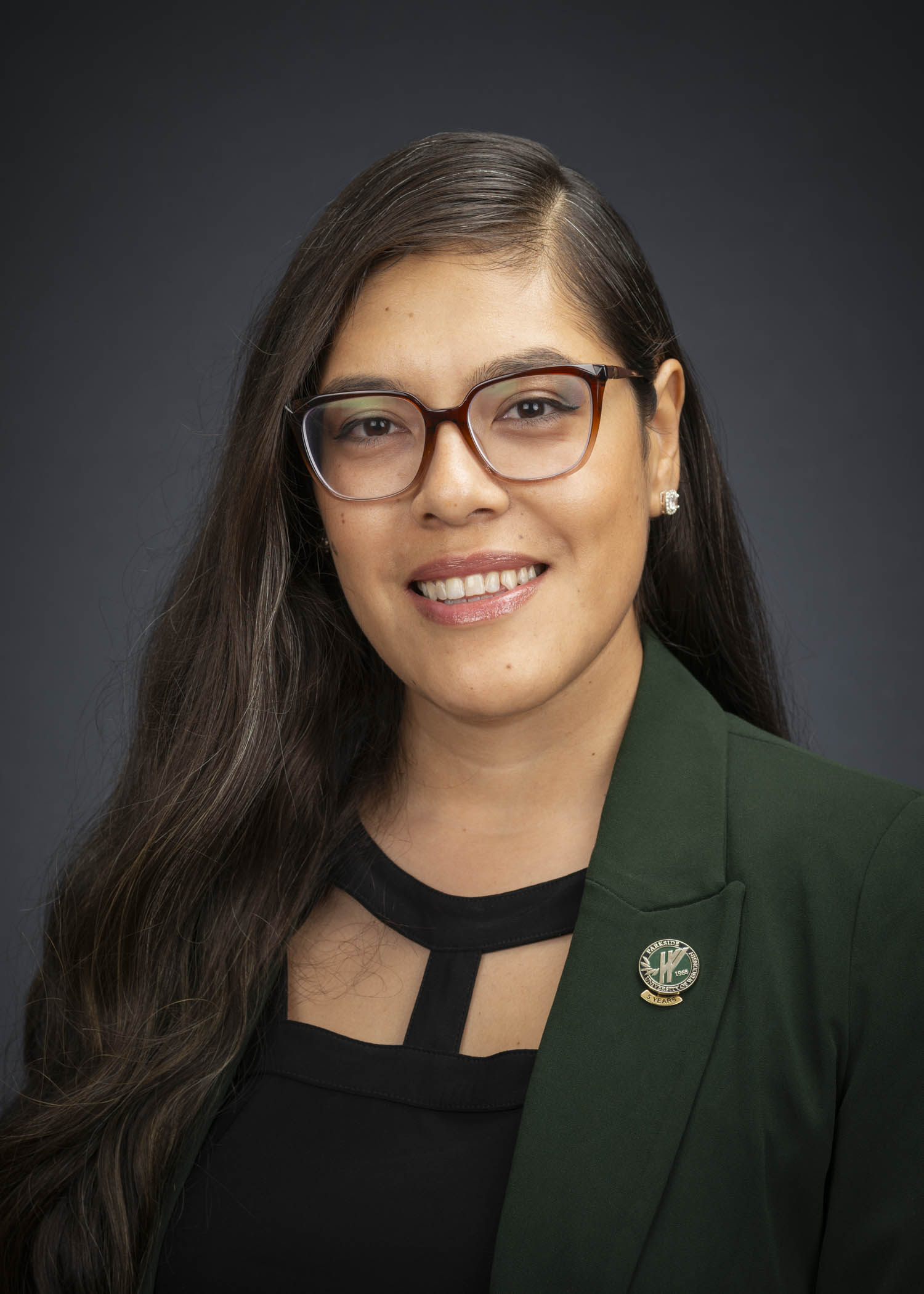 Latina woman with large frame glasses in green blazer