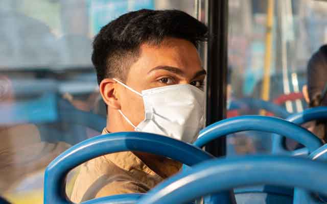 Hispanic teen on public transit wearing mask